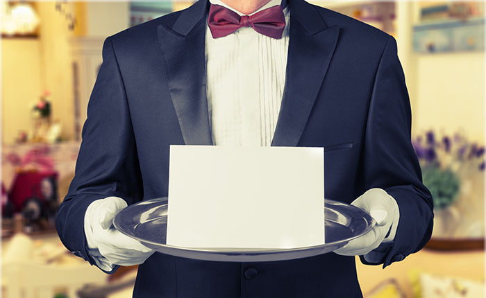 Hospitality Consulting a waiter holding a silver tray in front of his torso