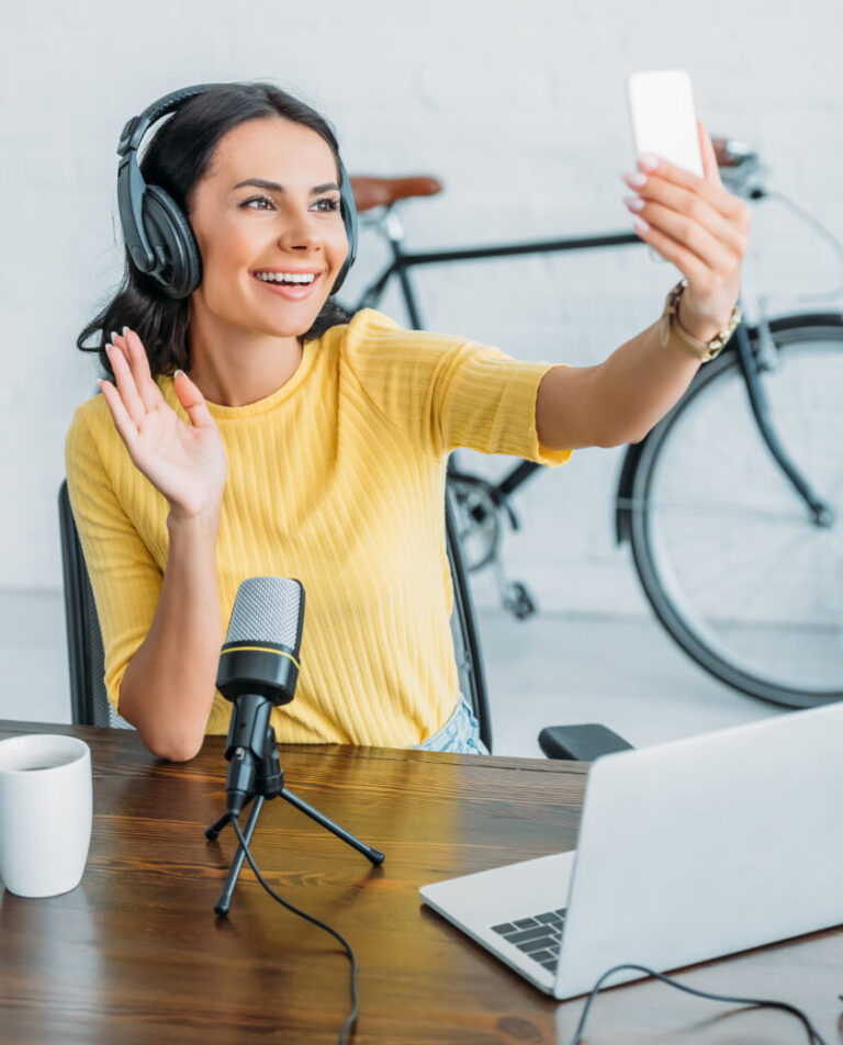 A girl in orange colour shirt having phone setting on chair for podcast